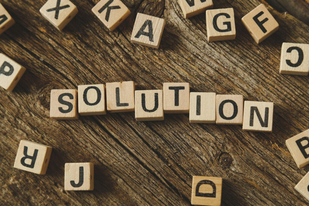 the word solution written out with wooden blocks that have letters painted on